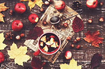 Cup of warming tea with apple and cranberry and yellow maple lea