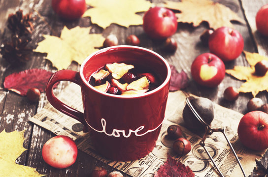 Tea with apple and cranberry and yellow autumn leaves