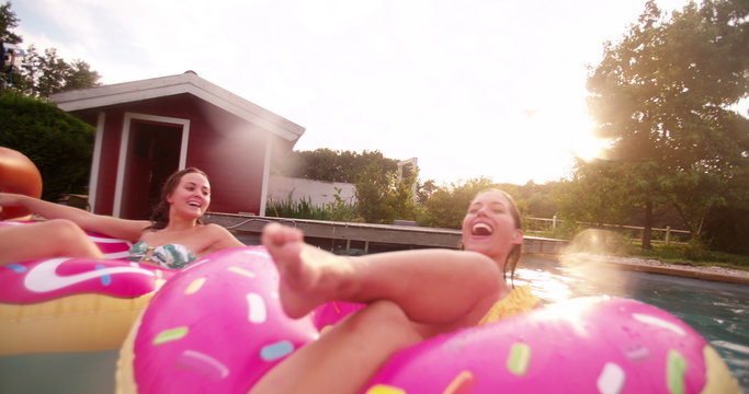 Girls playfully splashing in a backyard pool together in summer