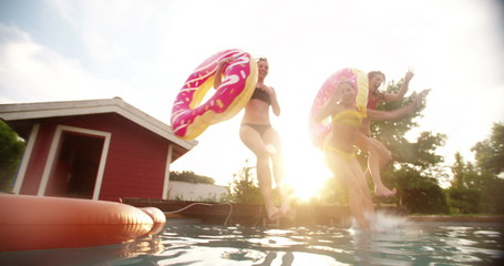 Girls jumping into a swimming pool on summer evening