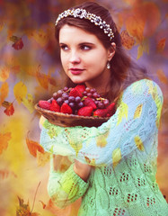 Autumn portrait of a woman with a bowl of strawberries and grapes