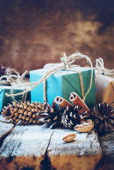 Christmas Gifts with Linen Cord, Cinnamon, Pine cones, Nuts on Wooden Background