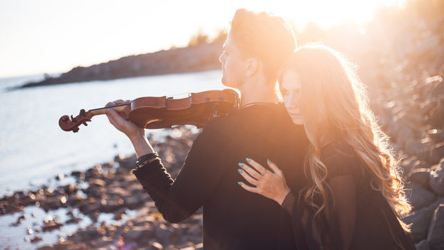 violinist and girl,  young man plays on the background of  sea