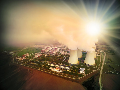 Aerial view to nuclear power plant in industrial landscape. Radiation and air pollution theme. Warm filtered picture.