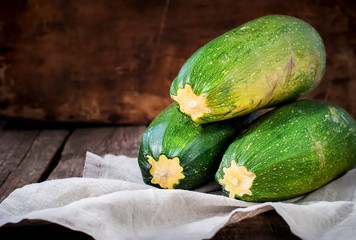 Simple Composition with Three Vegetable Marrow on Napkin. Wooden background