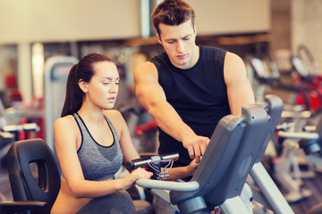 woman with trainer on exercise bike in gym