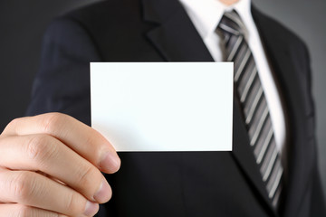 Geschäftmann in Anzug und Krawatte zeigt Visitenkarte mit Textfreiraum und Copy Space