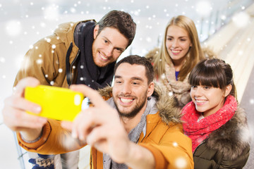 happy friends with smartphone on skating rink