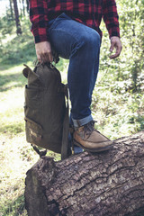 Detail of hiker resting with one shoe on tree trunk.