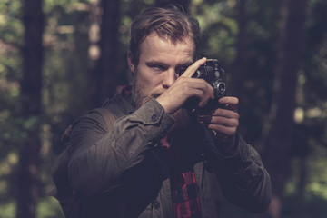 Close-up of man with beard photographing nature with vintage cam