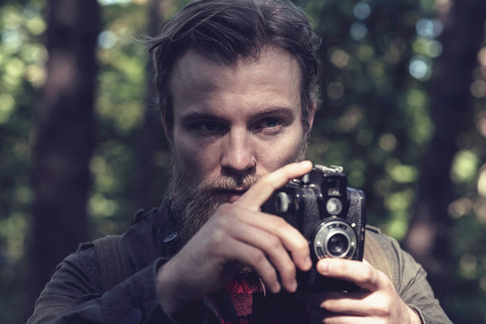 Close-up of man with beard photographing nature with vintage cam