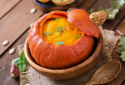 Pumpkin cream soup with peppers and herbs in a pumpkin
