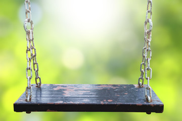 Rusty wood swing and blurry green backgrounds