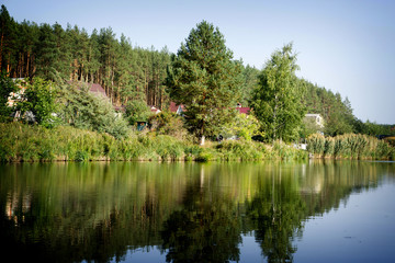 Fototapeta na wymiar River house with reflections and blue sky near the forest high contrasted with vignetting effect