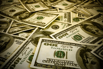 Mount of hundred dollar banknotes background texture warm filtered high contrasted with vignetting effect