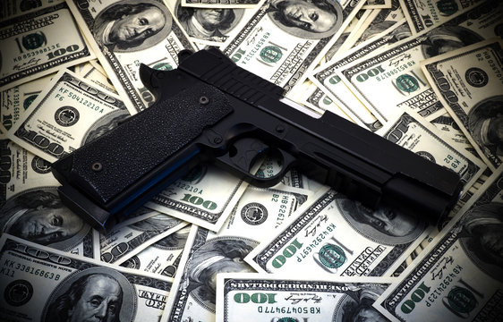 Black and chrome gun pistol and money dollars background high contrasted with vignetting effect 