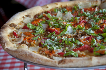 restaurant pizza with onions, sausage, basil, oregano, and red peppers,