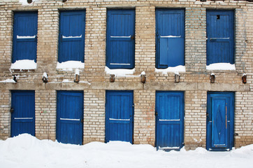 Fototapeta na wymiar Blue wooden doors, brick wall and snow.