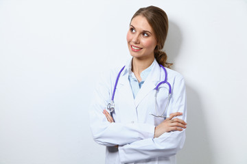 Fototapeta premium Friendly smiling young female doctor, standing near wall