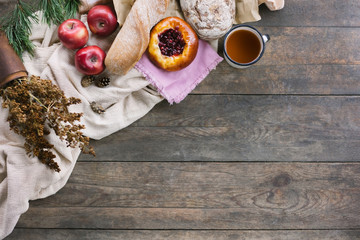 Булочка с клюквой, чай, яблоки и салфетки на столе