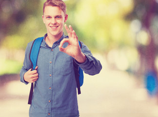 student man with back pack doing allright sign
