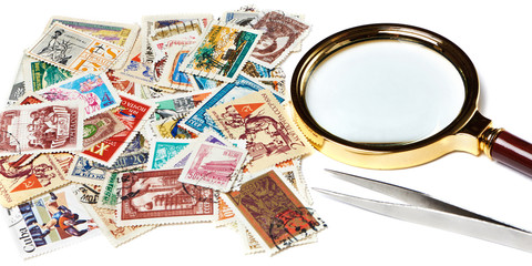 Old used postage stamps and magnifier