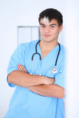 Portrait of unknown male surgeon doctor standing near the wall  in hospital office