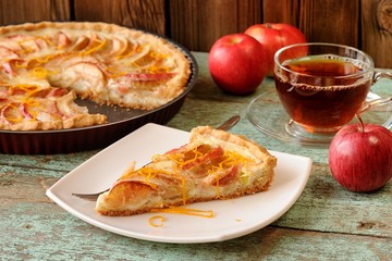 Homemade yummy open apple pie, black tea and whole red apples on