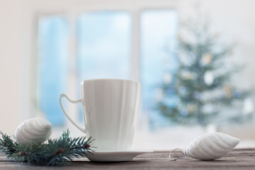white cup on background Christmas fir and window