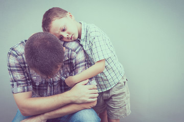 sad son hugging his dad near wall