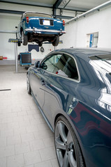 Fototapeta premium KFZ-Werkstatt von innen mit einem Auto auf einer Hebebühne