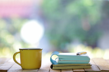 Notebook and yellow cup on wooden table