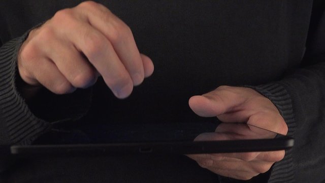 Hands with digital tablet computer in dark office interior