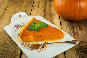 Thanksgiving pumpkin pie slice, mint on a wooden background