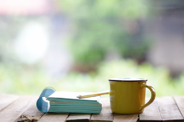 Notebook and yellow cup on wooden table