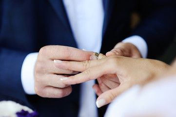 Groom wears a wedding ring a bride