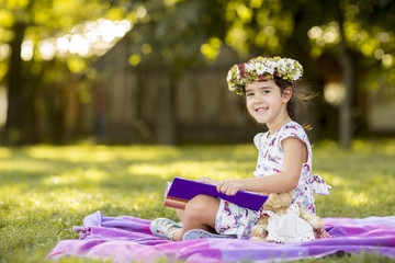 Fototapeta premium Little girl reading in the park