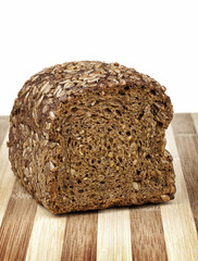 Rye bread mixed from many different healthy ingredients like pieces of soy, rye and wheat flour, sunflower seeds and barley. Studio shot. Photographed on interesting wooden table.