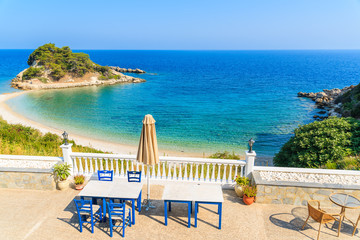 Tables with chairs on a terrace with view of beautiful Kokkari bay, Samos island, Greece