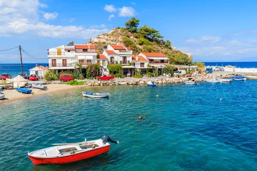 Papier Peint photo autocollant Île Fishing boat in Kokkari bay with colourful houses in background, Samos island, Greece