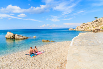 Couple of unidentified people relaxing on beautiful Kokkari beach, Samos island, Greece