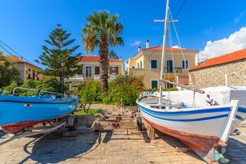 Fishing boats in dock of Pythagorion port with traditional colourful Greek houses in background,...