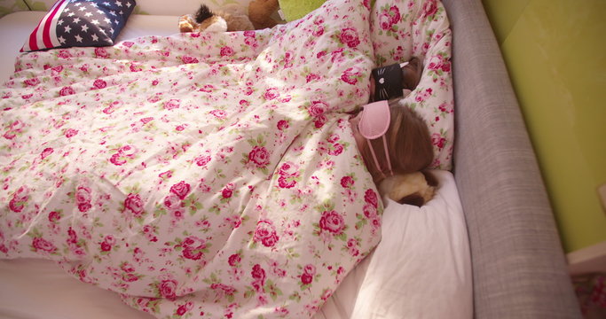 Adolescent girls hiding under the bed covers with sleeping masks