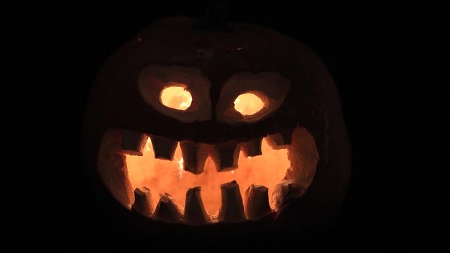 gruseliger Halloween-K&uuml;rbis mit geschnitztem Gesicht und im dunkeln leuchtende Funken 
 