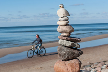 Fototapeta na wymiar Stones pyramid with cyclist at sea.