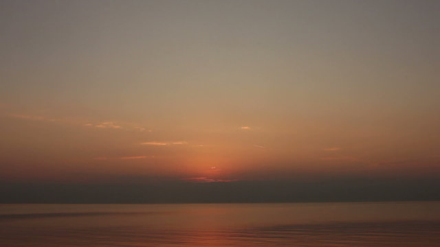Last bits of sun is setting over water with gentle waves. Fast forward time lapse clip.