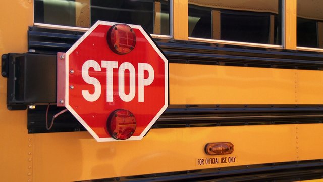 Stop sign on side of a bright yellow school bus, slow zoom in, 4K, Ultra HD
