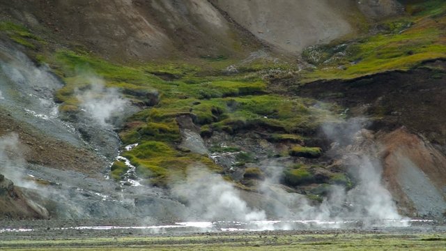 Steam rising up from hot springs in the earth in the colorful mountains of the Landmannalaugar area in Iceland.