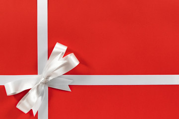 White satin bow gift ribbon border frame for birthday or christmas present on red wrapping paper background photo