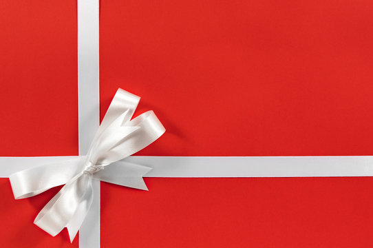 White satin bow gift ribbon border frame for birthday or christmas present on red wrapping paper background photo